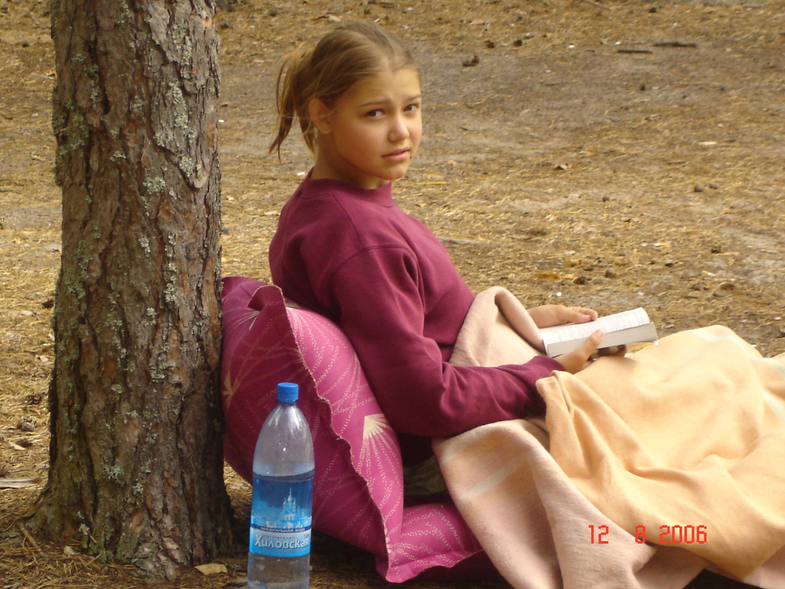 Арина в детстве читает книгу под деревом